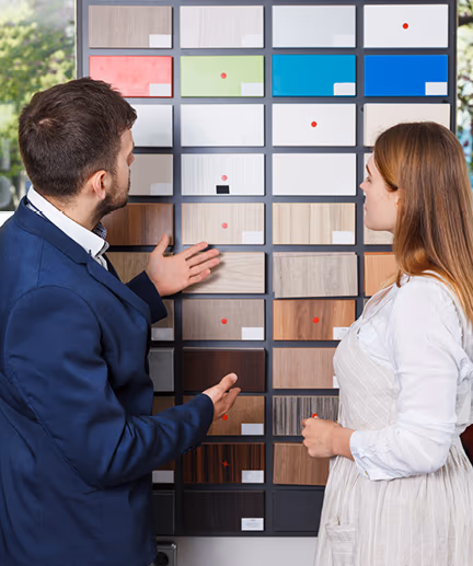 Fachverkäufer berät Kundin bei der Auswahl verschiedener Holzoberflächen.